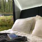 Säng i husvagn med utsikt mot tjärn